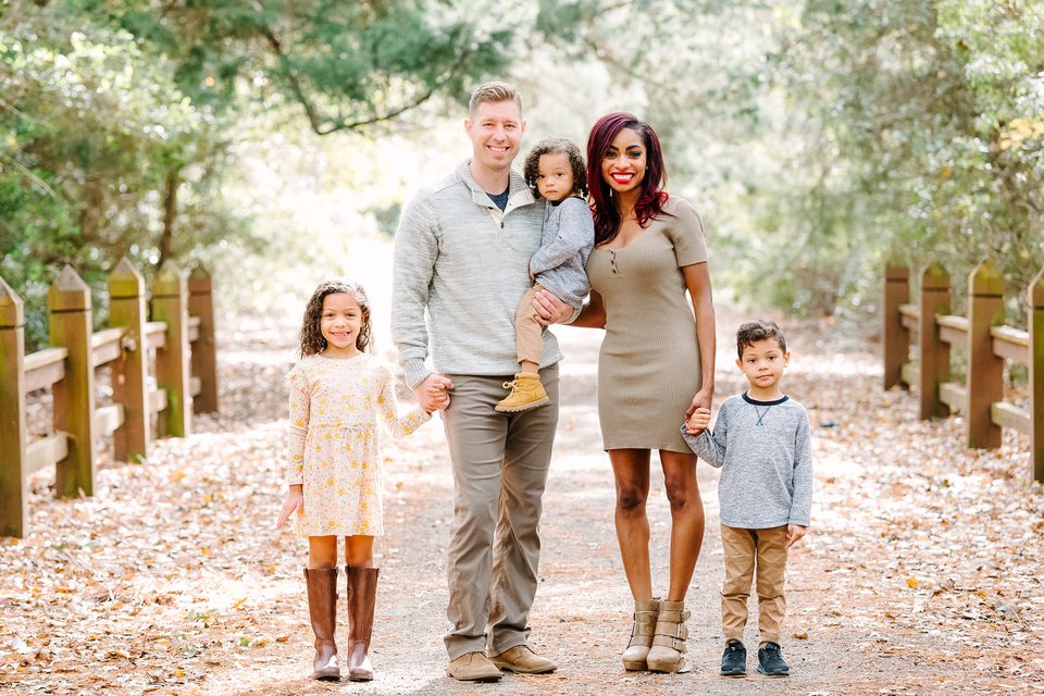 Family of five standing together on a wooded path