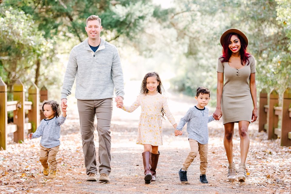Family walking hand in hand along a wooded path