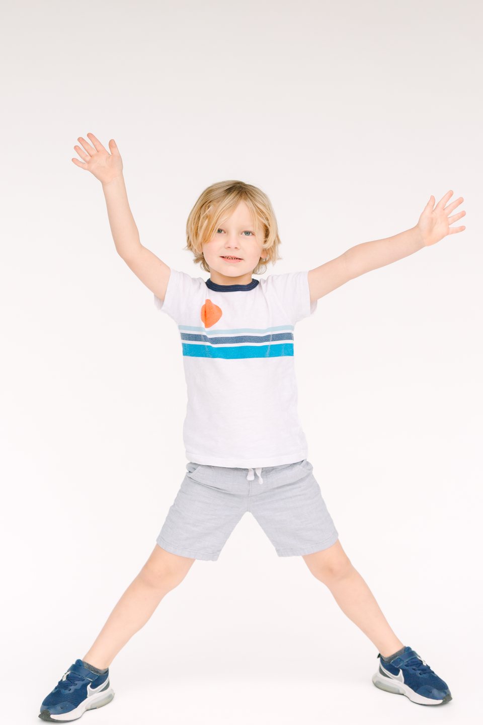 Boy leaping with arms and legs spread wide in the studio