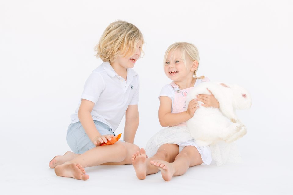 Brother and sister sitting with a white bunny in the studio