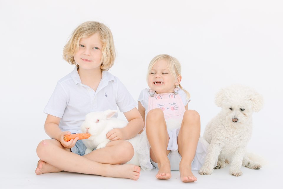 Brother and sister with a bunny and a small white dog in the studio