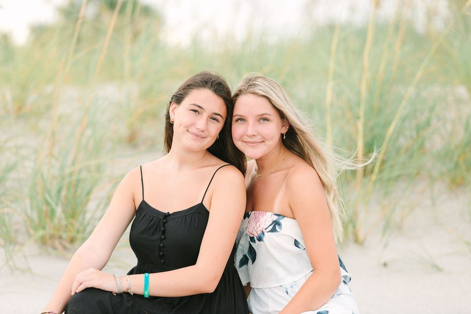 Two friends sitting close together in the dune grass