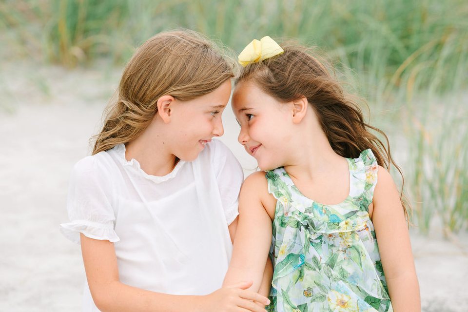Two sisters touching foreheads in the dune grass