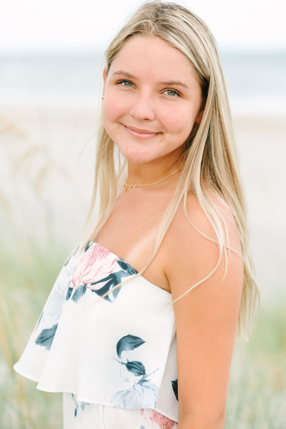 Young woman in a floral top smiling at the beach