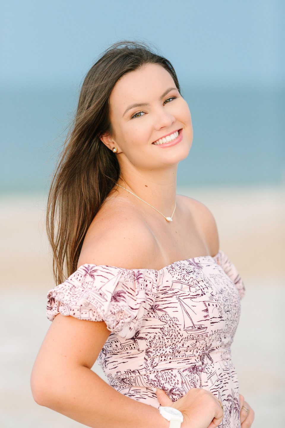 Smiling young woman in a patterned dress against blue water