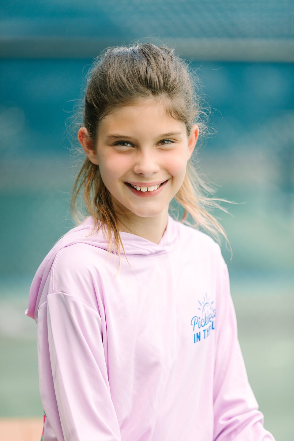 Smiling girl in a pink hoodie against a blue background