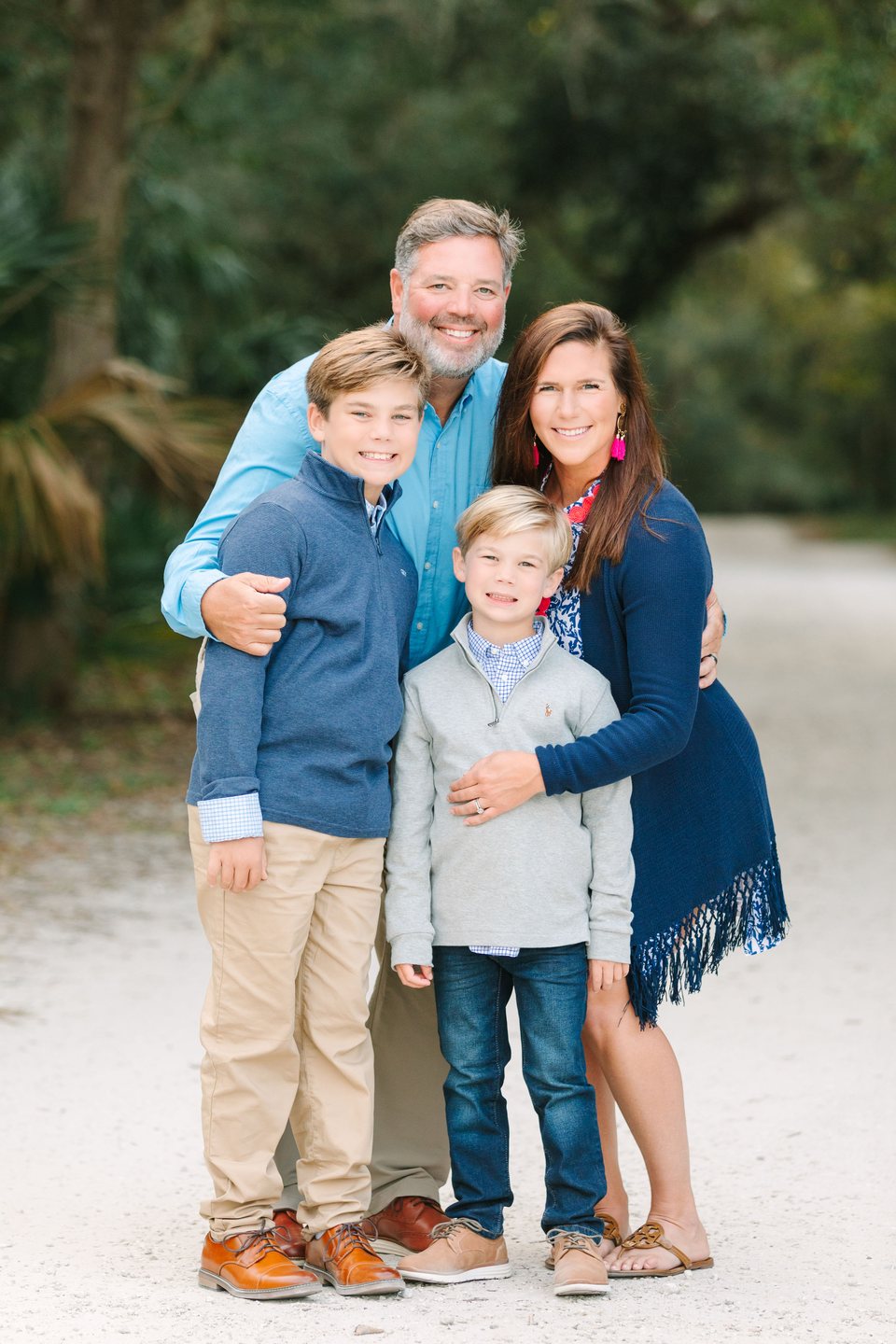 Family of four gathered closely on a sandy path