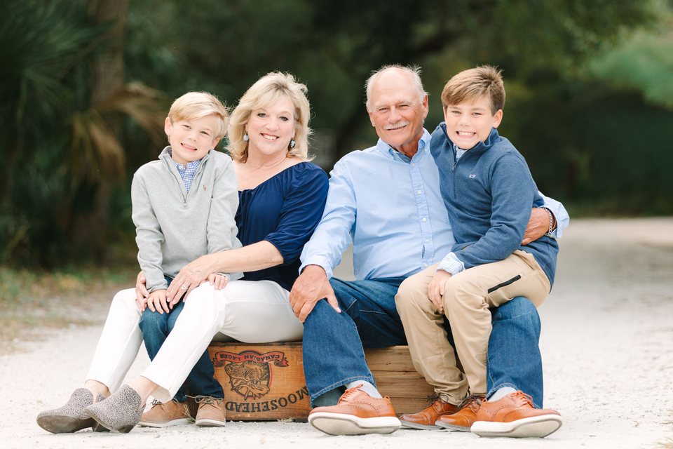 Grandparents seated on a crate with two grandsons on a beach path