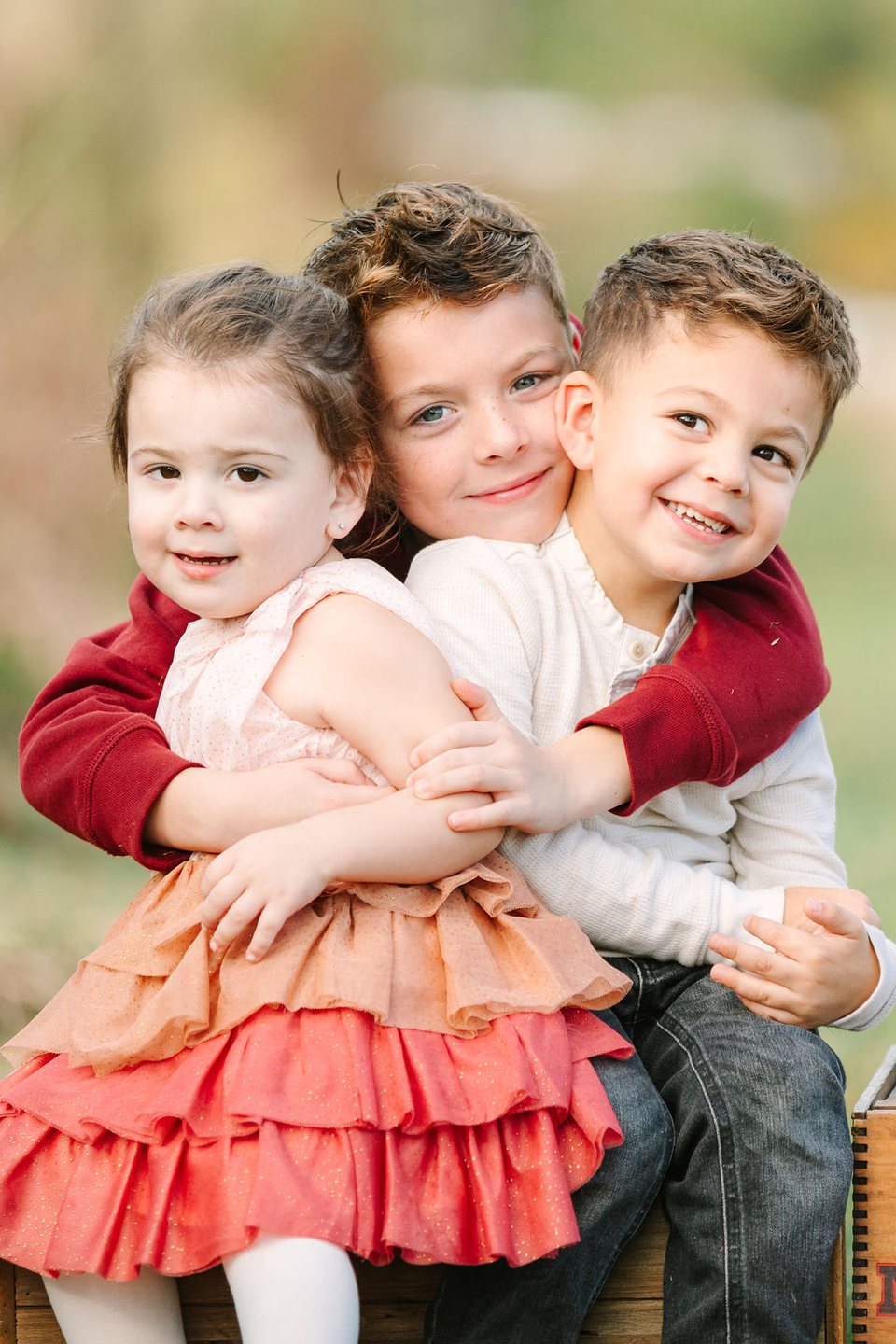 Three young siblings squeezed into a hug