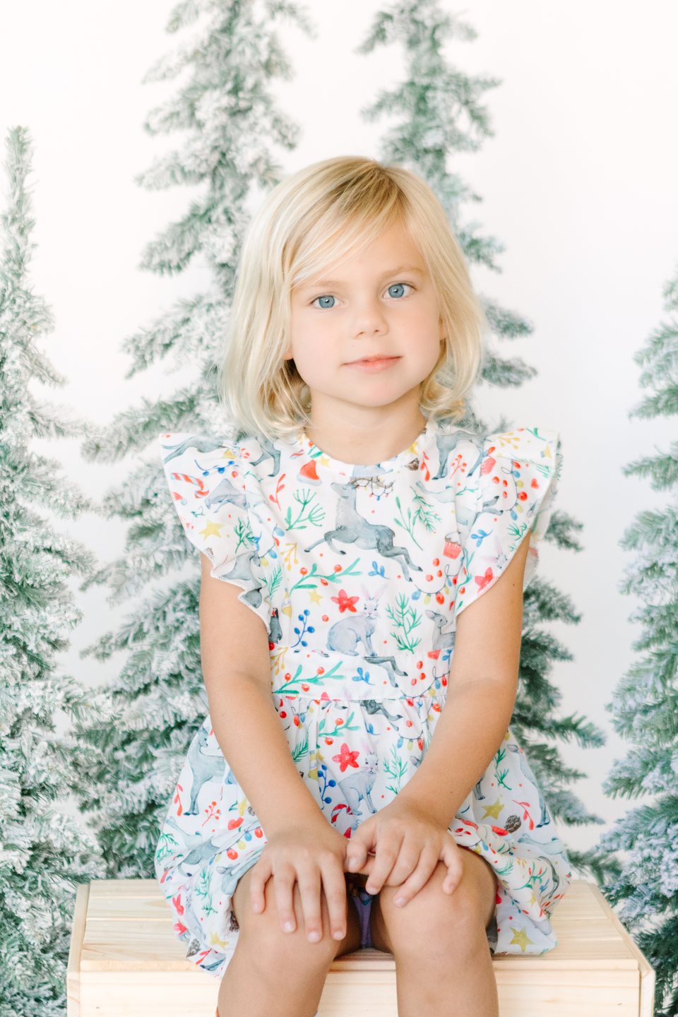Child in a floral dress between snowy trees in the studio