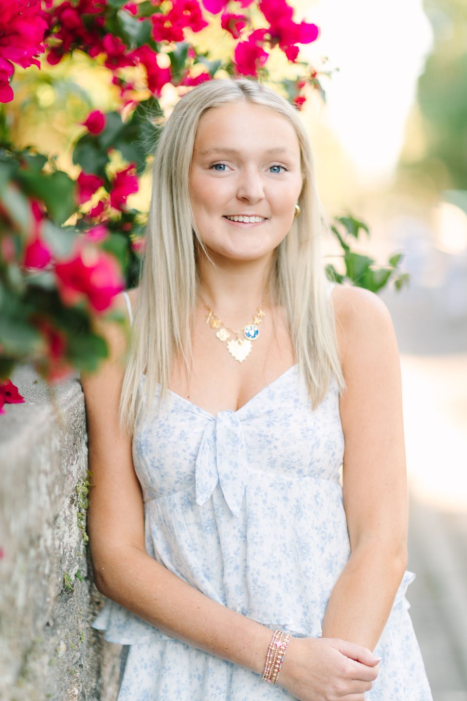 Young woman smiling beneath bright red flowers