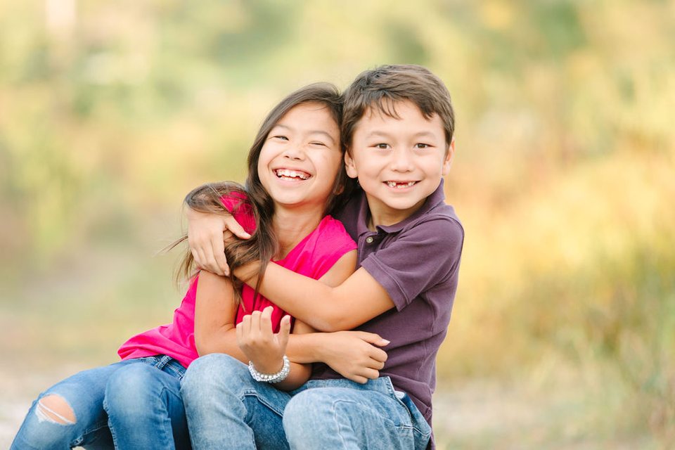Brother and sister hugging in a golden field
