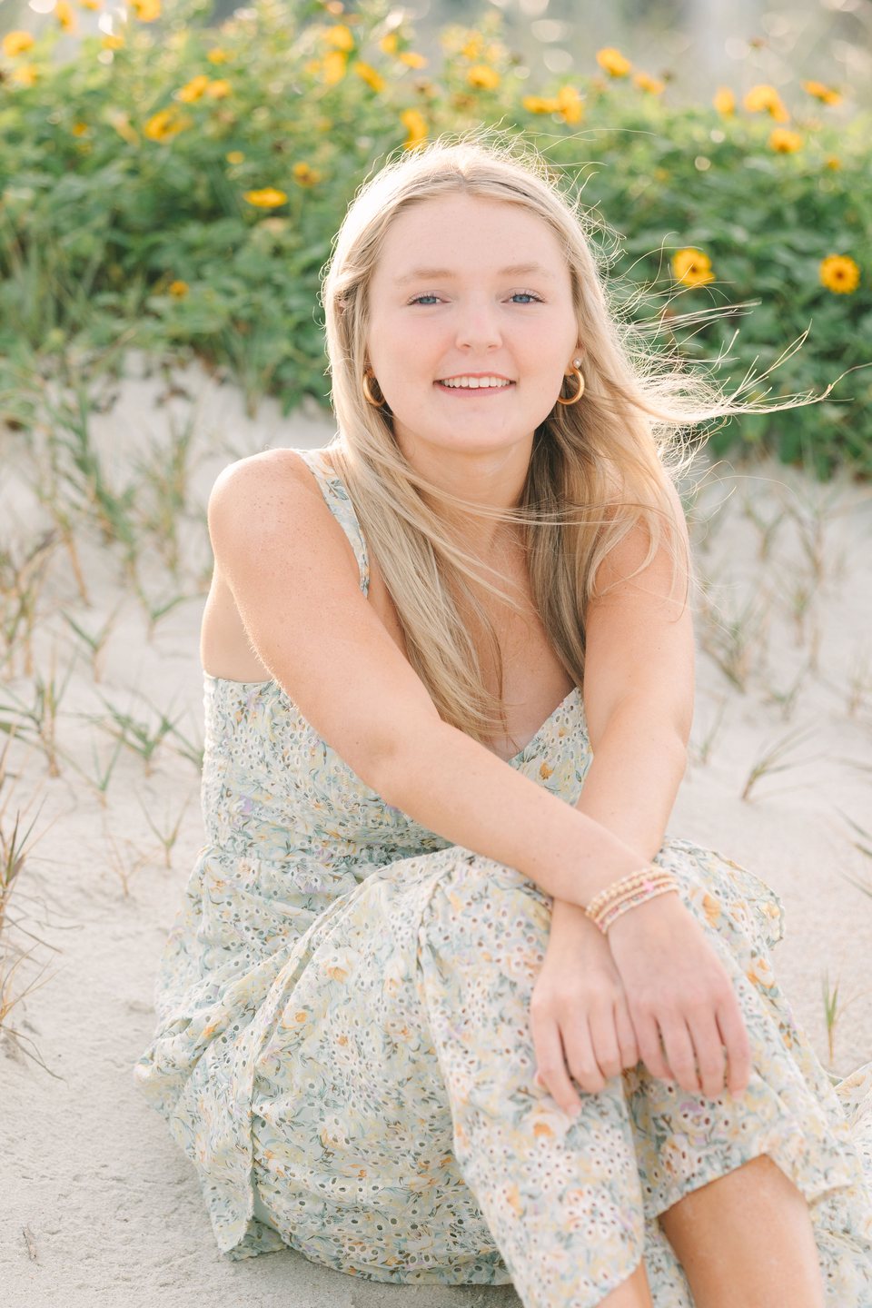 Young woman smiling among yellow wildflowers at the beach