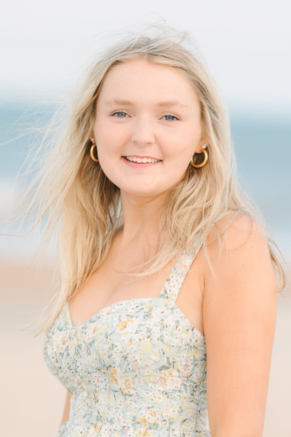 Young woman with wind-blown hair smiling at the beach