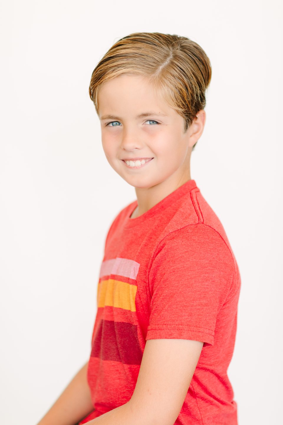 Boy in a red tee smiling in the studio