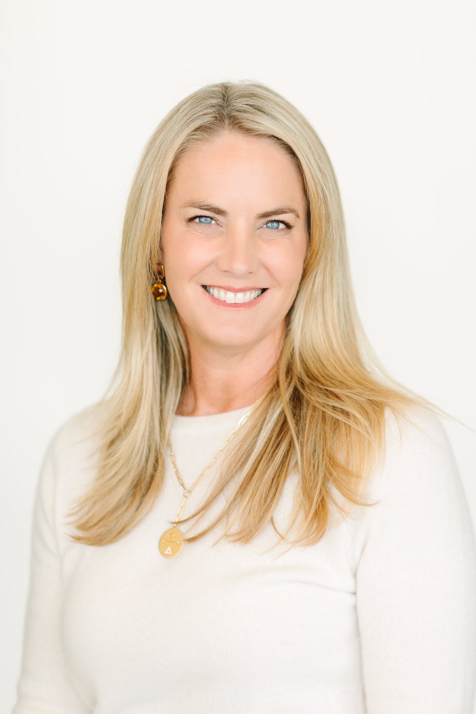 Headshot of a smiling woman with blonde hair in a white top