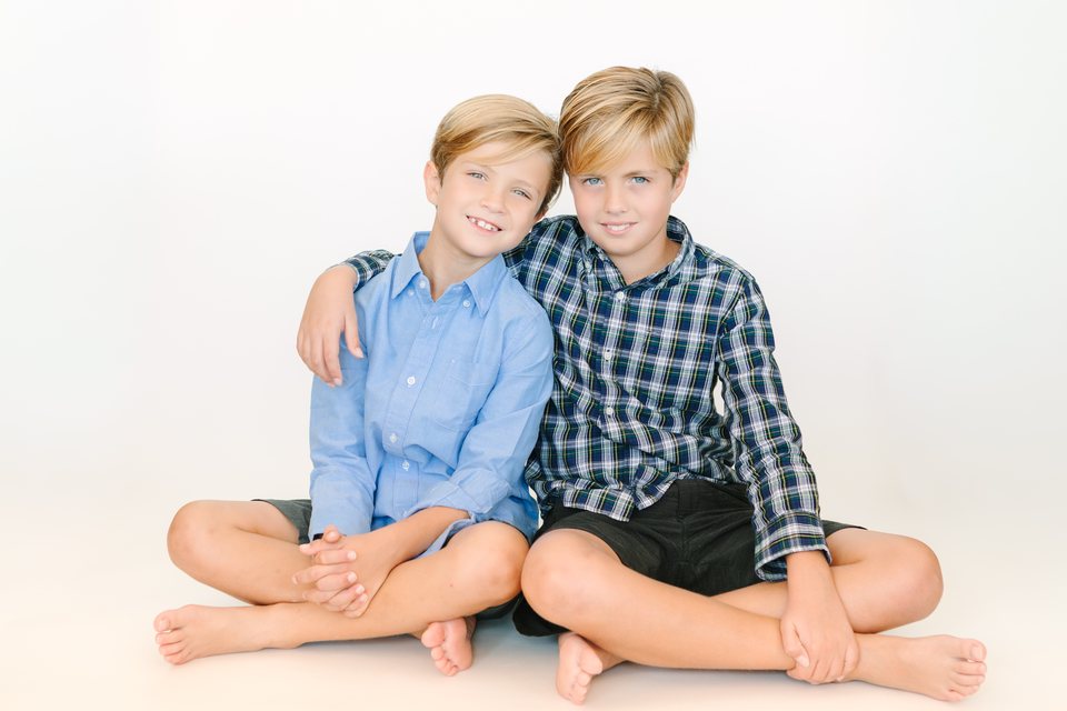 Two brothers in plaid and blue sitting together in the studio