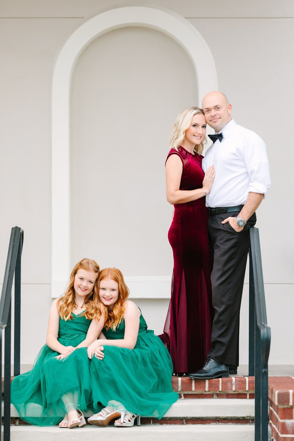 Family in festive dress in front of a white arched doorway