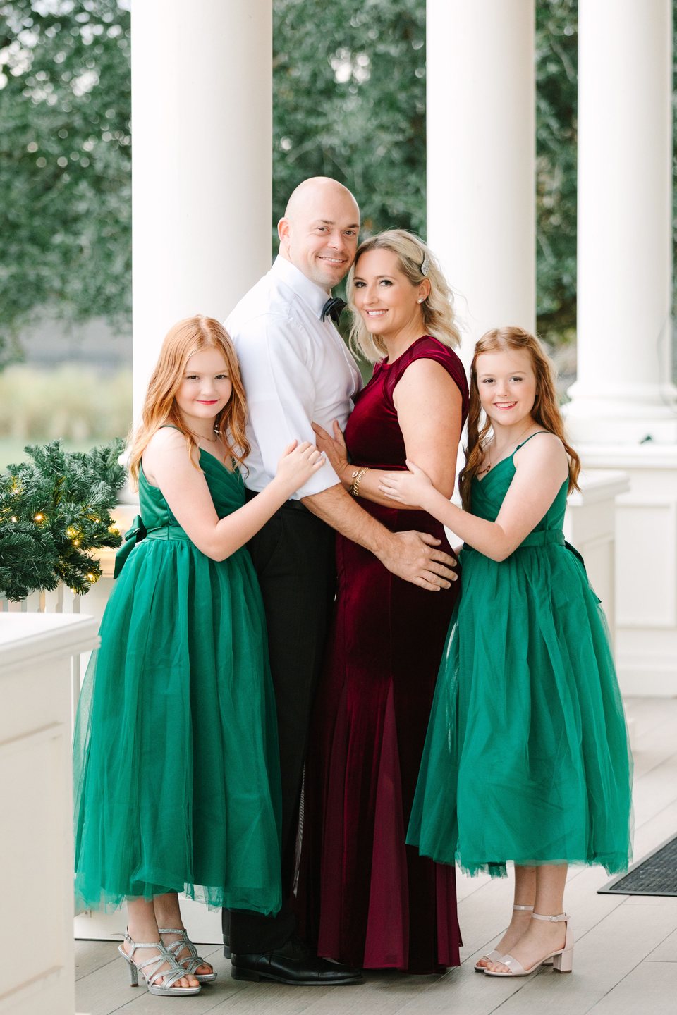Family of four in emerald and burgundy on a white-columned porch
