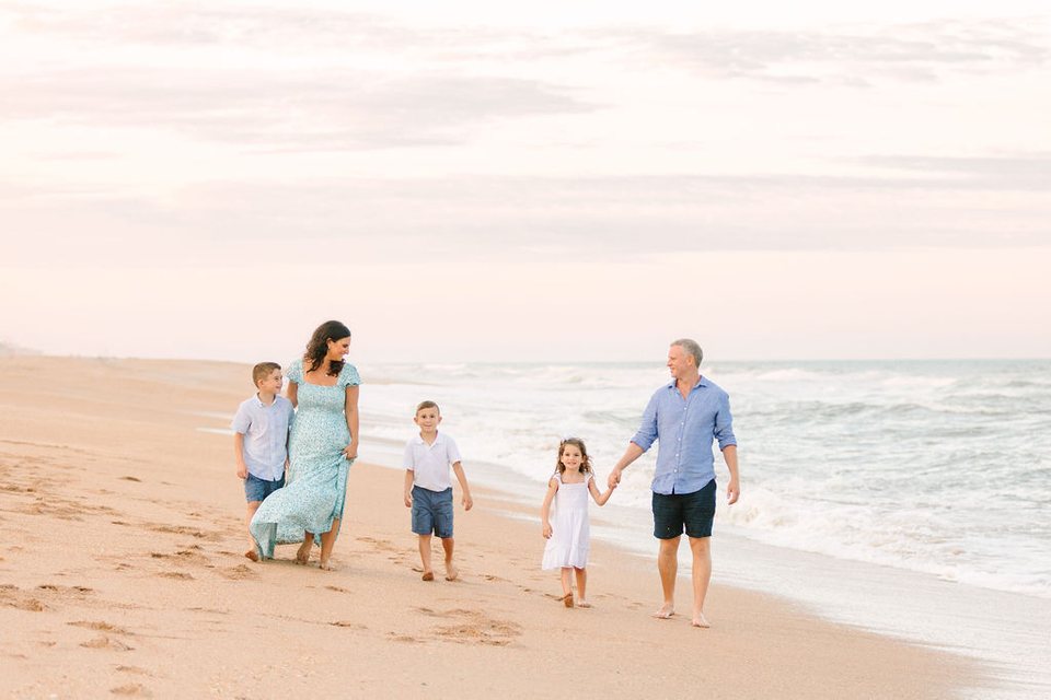 Family walking hand in hand along the beach at sunset