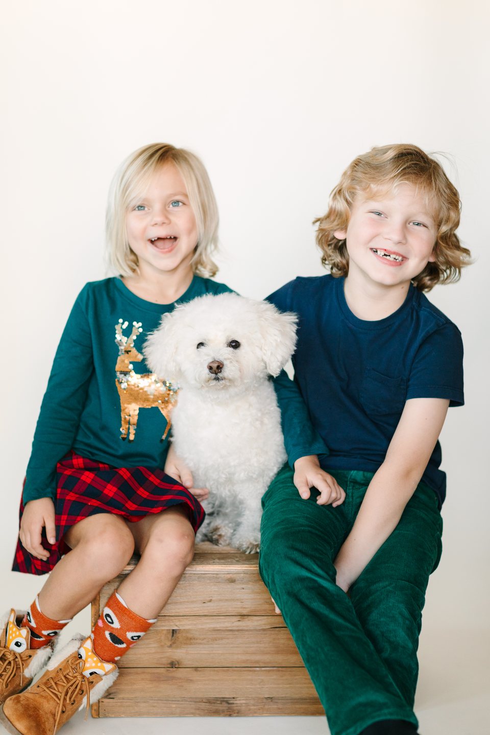 Brother and sister with a small white dog on a wooden crate
