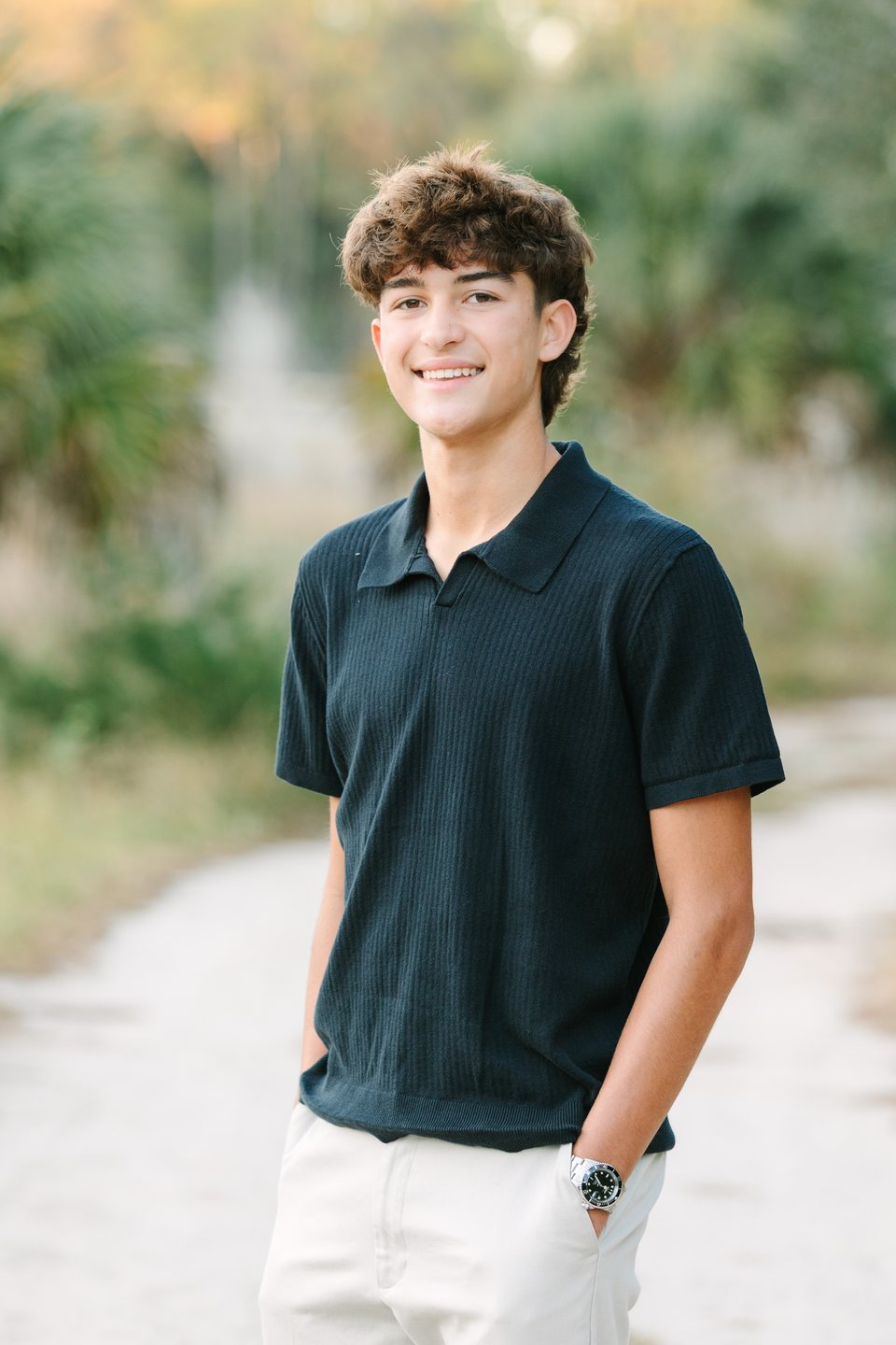 Teen boy in a navy polo on a sandy path