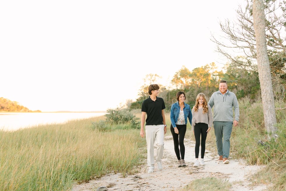 Family of four walking a sandy path toward the water