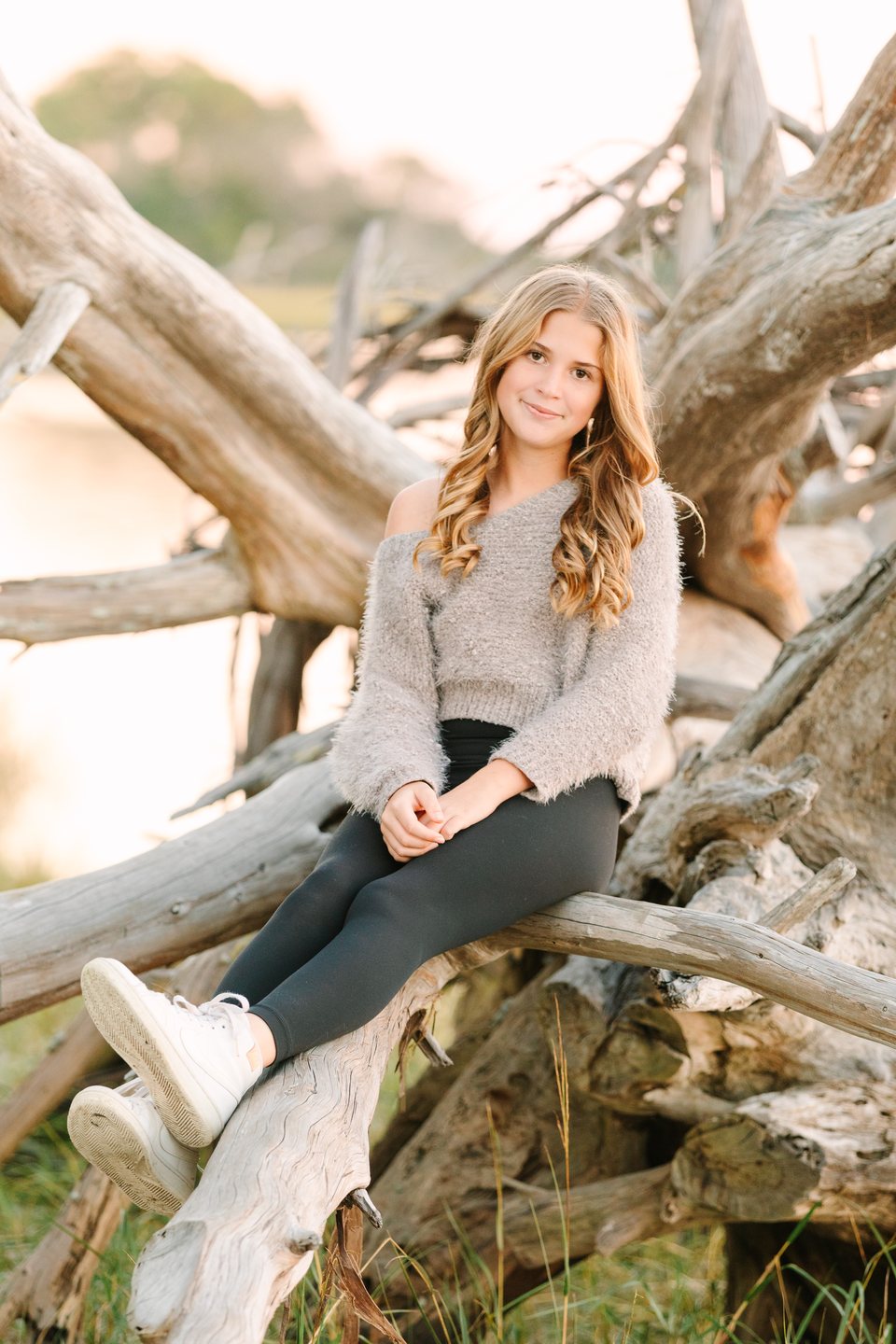 Teen sitting on driftwood beside the water
