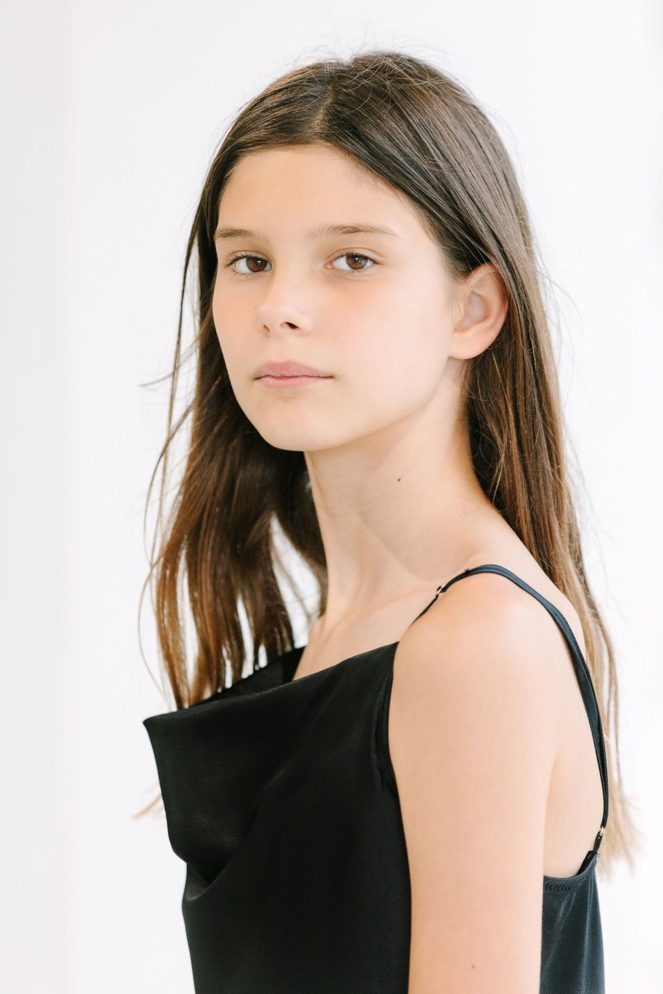 Studio portrait of a girl with long dark hair in a black top