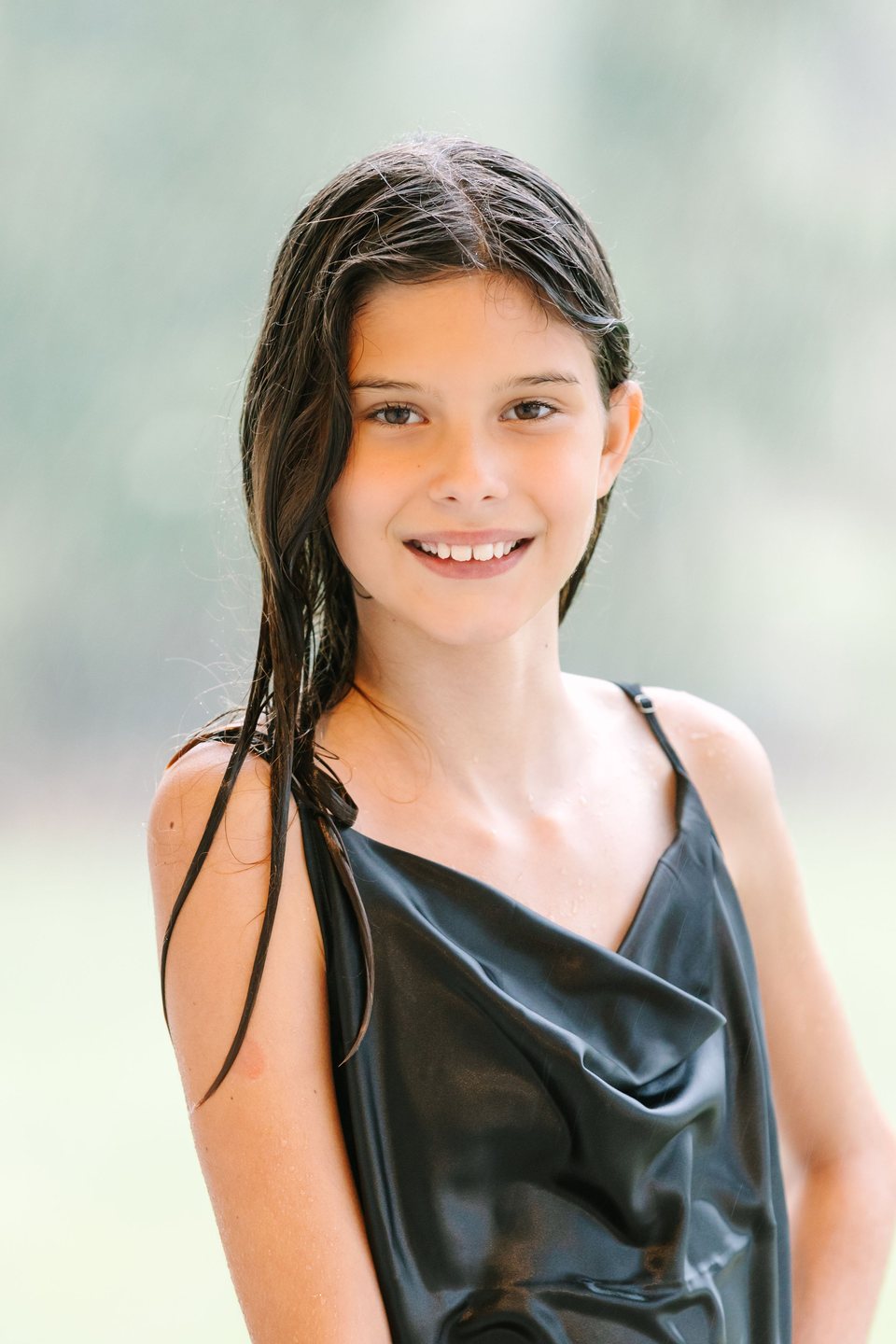 Child in a black dress smiling in soft green light