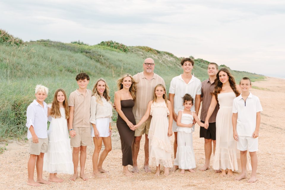 Large extended family standing together on the beach in front of the dunes