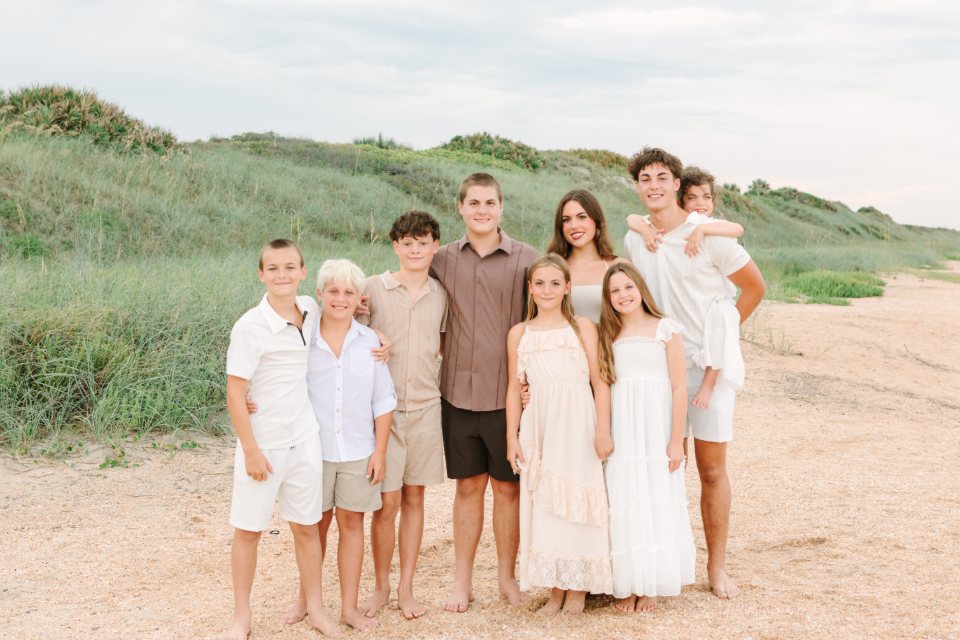 Extended family gathered on the sand with grassy dunes behind them